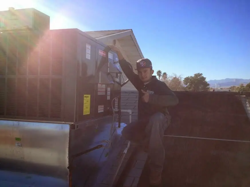 HVAC technician performing Heat Pump Repair on a rooftop unit in Center Line